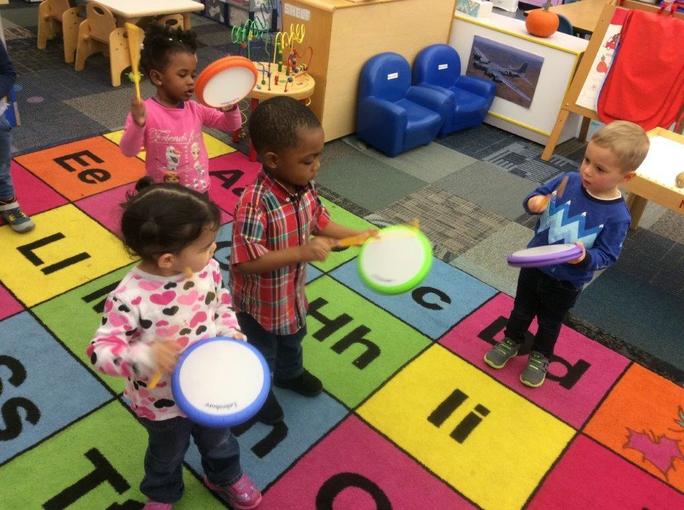 A group of children at Glendale Heights Child Care in Glendale, WI playing with drums on top of foam letter blocks